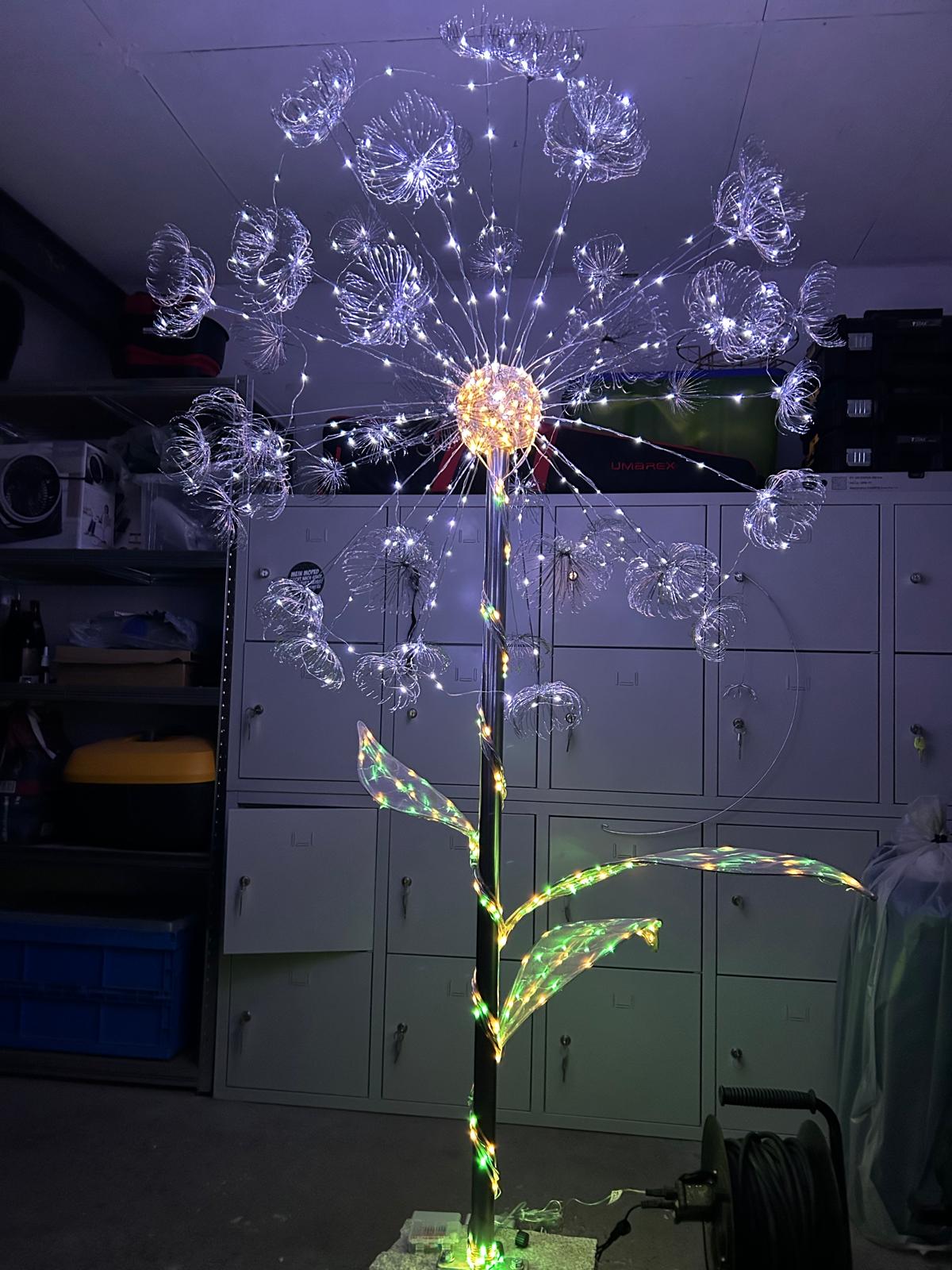 Große Pusteblume mit weiß leuchtenden Schirmchen, goldener Mitte und grün-goldenem Stiel in der Werkstatt